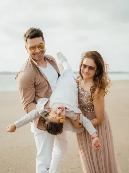A fun and playful family moment on the sand, with the birthday boy held upside down. These candid shots create the best memories.