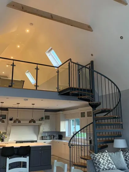 The completed spiral staircase, viewed from the living space. The design complements the high ceilings and adds a strong vertical element to the room.