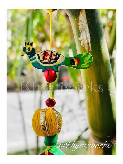 A detail of the hand-painted bird that sits atop the kite wall hanging, adding a touch of nature and whimsy.