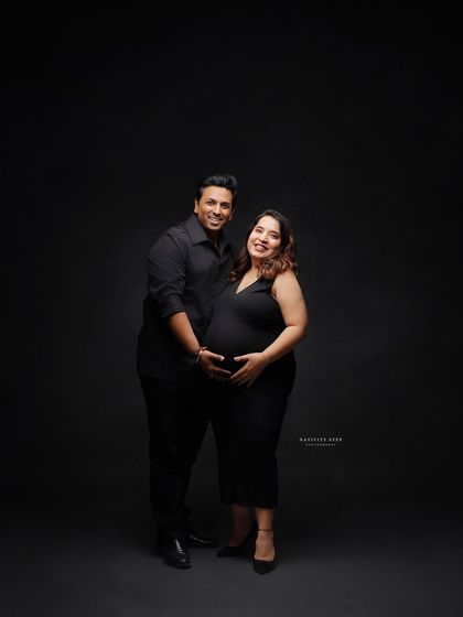 A classic and happy couple's portrait. Dressed in matching black, their smiles and embrace show their shared joy and excitement.