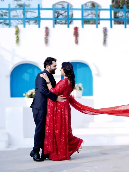Our Santorini-inspired set provides a stunning Mediterranean backdrop without leaving the city. The vibrant red of the flowing dress contrasts beautifully with the classic white and blue architecture, perfect for a destination-themed pre-wedding shoot.