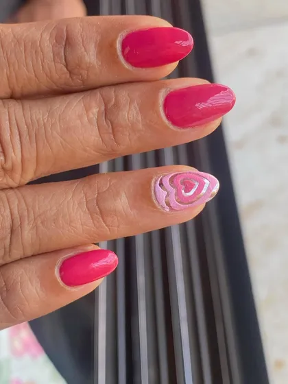 A simple and sweet design with a solid pink manicure and a single accent nail with a layered heart design.