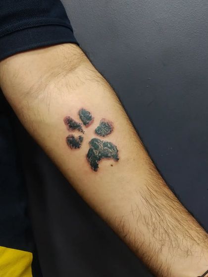 A realistic dog paw print tattoo. This was created from an actual print of the client's beloved pet, making it a very personal and heartfelt tribute.