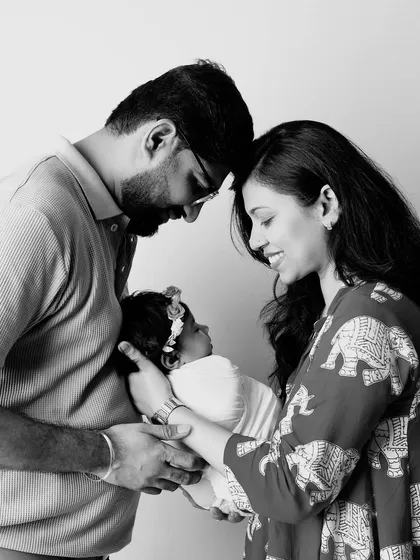 A beautiful black and white photo capturing the intimate bond of a new family, their heads close together as they admire their baby.
