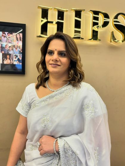 A client looking elegant in a saree, with her hair styled in soft waves after a fresh global color treatment. The color adds richness and complements her sophisticated look.