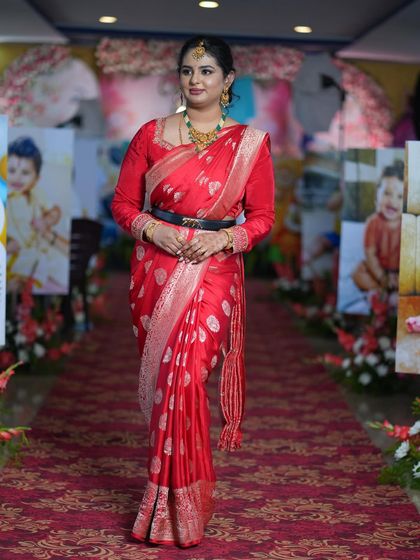 A full-length view of Prathibha's outfit, showing how the makeup and styling complement her entire look as she walks through the beautifully decorated venue.