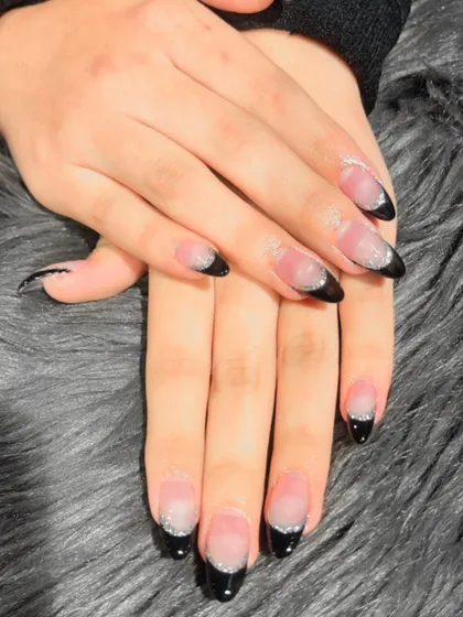 A modern twist on a classic. These almond-shaped extensions feature a sharp black French tip with a subtle silver glitter fade, creating a sophisticated and edgy look.