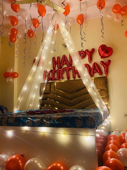 The birthday setup seen from the foot of the bed, showing the floor covered in balloons for an extra touch of fun.