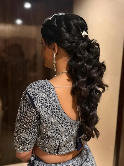 The back view of a stunning braided ponytail with soft curls. This hairstyle adds volume and texture, creating a glamorous and sophisticated look that is perfect for a reception or sangeet.