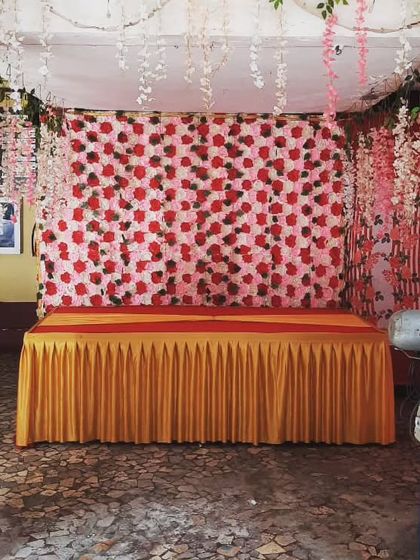 A simple backdrop for a home Ganpati celebration. The red and white flower wall with hanging wisteria is a beautiful and easy way to decorate.