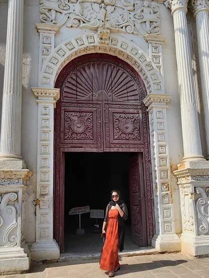 Exploring the historic Saint Paul Church in Diu. A comfortable rust-colored maxi dress with a black shrug is perfect for sightseeing in style.