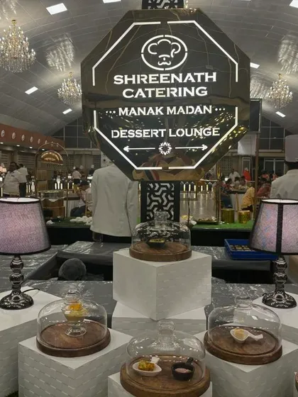 This is a view of one of my full-scale Dessert Lounge setups for a large wedding. The custom-lit octagonal sign and elegant displays with glass cloches create a sophisticated and inviting atmosphere for guests to gather.