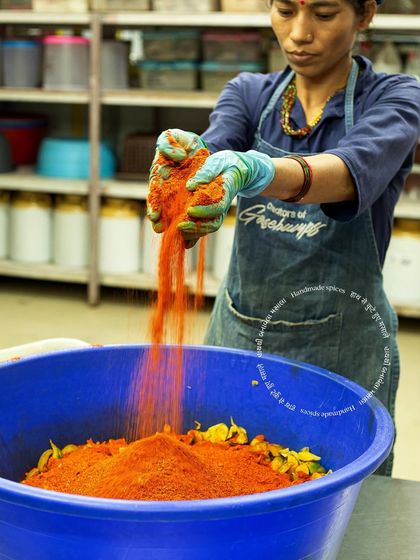 Here, one of our team members mixes the hand-pounded spices into the mango pieces. This hands-on approach ensures every batch of Khatti Keri pickle is perfectly seasoned.