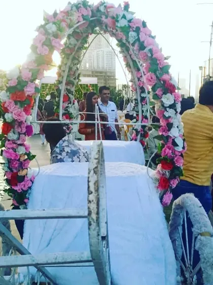 A decorative horse-drawn carriage, or 'buggy', adorned with pink and white flowers, used for the bride or groom's grand entrance at an outdoor wedding.