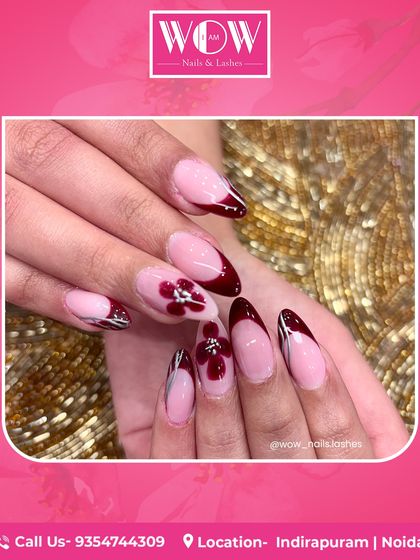 A stunning floral design on long, almond-shaped nails. This look combines a deep burgundy French tip with intricate, hand-painted flower details.