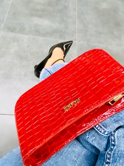 A close-up showing my favorite color combination. A textured red clutch against classic blue denim and sharp black heels is a simple way to make a powerful style statement. It's a timeless trio.