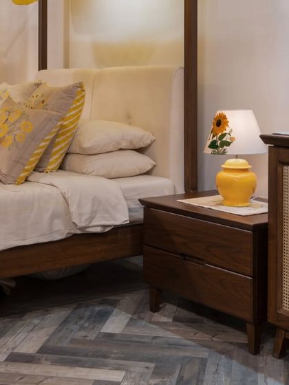 A side view of the four-poster bed and custom nightstand. The combination of solid wood, a natural cane panel, and soft upholstery creates a piece that is rich in texture and grounded in sustainable, natural materials.