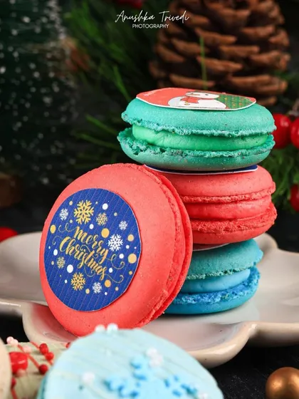 A stack of colourful Christmas macarons. The close-up shot highlights the custom "Merry Christmas" prints, making them a perfect personalized festive gift.