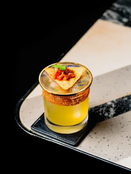 Who says your drink can't have a snack? This savory cocktail is garnished with a nacho chip and salsa, offering a unique and flavorful twist.