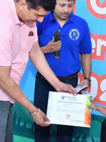 A close-up of a young student receiving her certificate of participation from our chief guest. This moment represents the culmination of her efforts and learning during the summer camp.