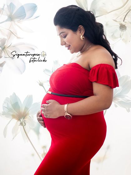 A simple and beautiful side profile in a red gown against a soft, floral-patterned backdrop.