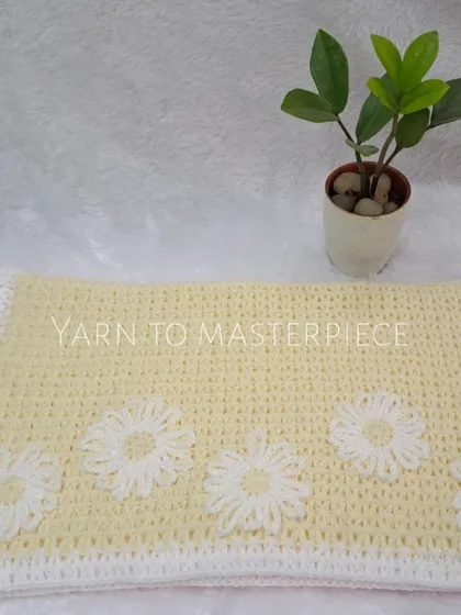 A beautifully styled shot of the yellow and white daisy blanket, showing how it can be a lovely, soft addition to any room.