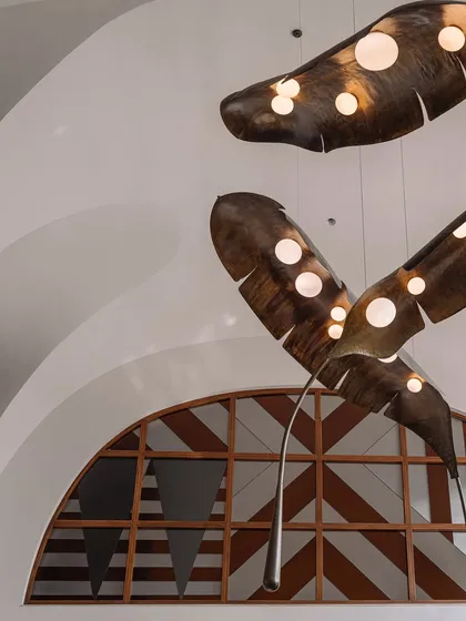 Lighting can be the jewelry of a space. In this double-height living room, we collaborated with artists to create this dramatic installation of oversized, illuminated metal fronds. The piece fills the grotto-inspired ceiling, casting a warm glow and acting as a magnificent sculptural focal point.