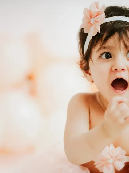What a face. This expressive close-up captures a moment of surprise and delight during a simple session with a pink balloon backdrop.