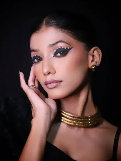 A classic beauty shot, with the model's hand gently framing her face, drawing attention to the artistic makeup.