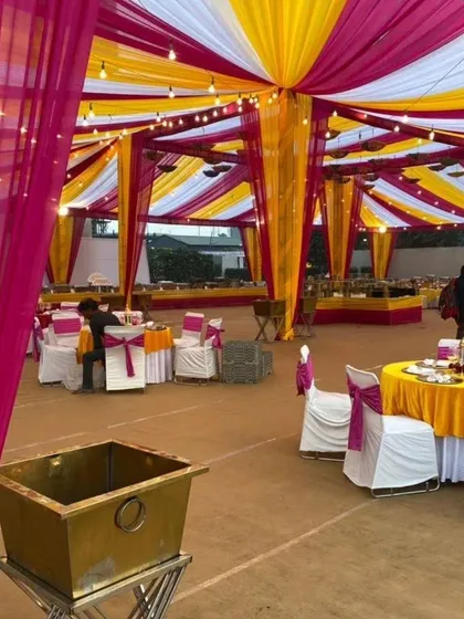 A large tented area for a wedding function, decorated with pink and yellow drapes. This shows my capability to handle catering and seating arrangements for large crowds.