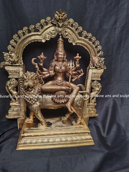 A powerful bronze sculpture of Goddess Durga, seated on her lion and framed by a Prabhavali. She holds the divine weapons given to her by the gods to vanquish evil.