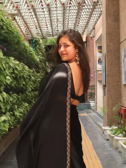 Looking back with a smile. This pose shows off the beautiful backless design of the blouse, a key detail of the outfit.