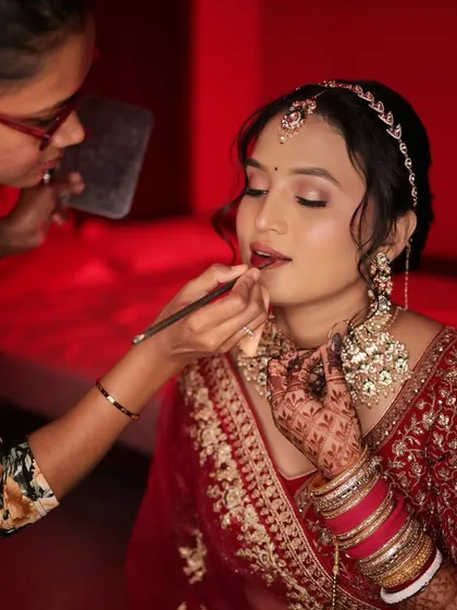 Applying the final touches to the bride's lips, a crucial step for a long-lasting and perfect pout.