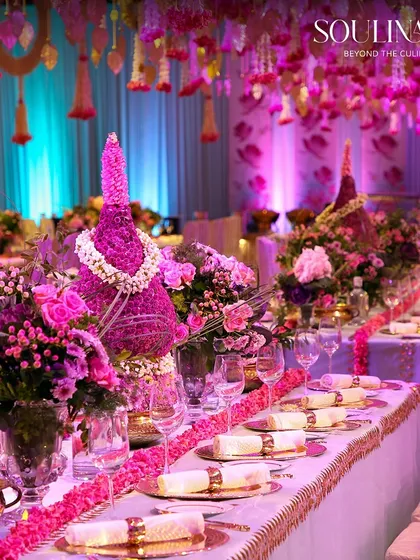 An ethereal wedding reception where tables are adorned with magnificent pink floral arrangements and elegant place settings. We design breathtaking visual narratives that make your most important celebrations truly unforgettable.