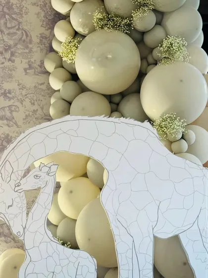 A close-up of our Dior-inspired safari theme, featuring elegant giraffe cutouts against a backdrop of white balloons and baby's breath.