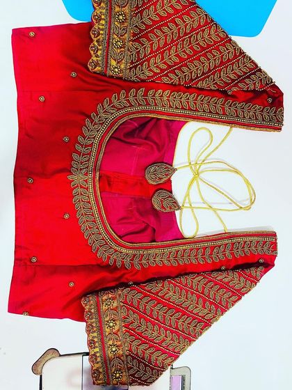 This bright red blouse features heavy, traditional leaf-motif embroidery in gold thread. The work covers the entire sleeve and neckline, making it perfect for a pattu saree.
