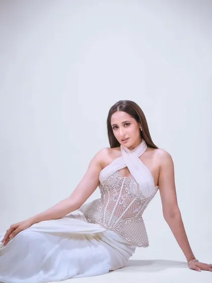 This signature look features an intricately embroidered sheer corset with a halter neckline. Paired with a draped skirt, it radiates a timeless beauty and effortless elegance.