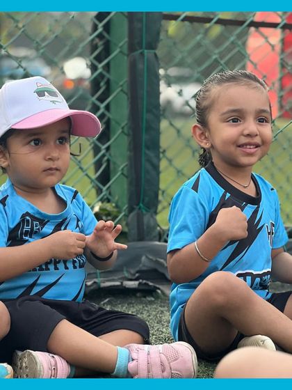 Two friends sitting side by side, fully engaged in the session. We love seeing these little friendships blossom on the field during our summer football camps.
