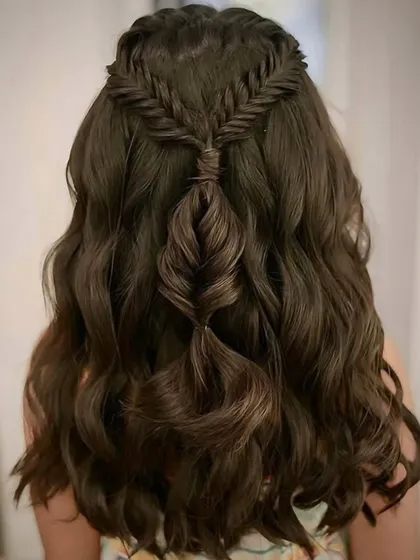 An example of our intricate braiding work. This half-up style features a fishtail braid flowing into soft, cascading waves, a beautiful style for younger clients or for a bohemian-inspired look.