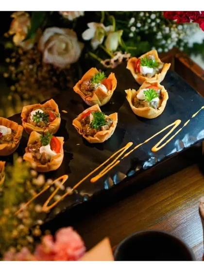 Savoury tartlets filled with a creamy mushroom mixture and garnished with fresh herbs. The artistic drizzle of sauce on the slate platter demonstrates our commitment to beautiful plating.