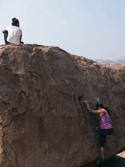 A climber tackles a highball boulder while another spots from the top. Our sessions are about finding your own challenge and having fun with it.