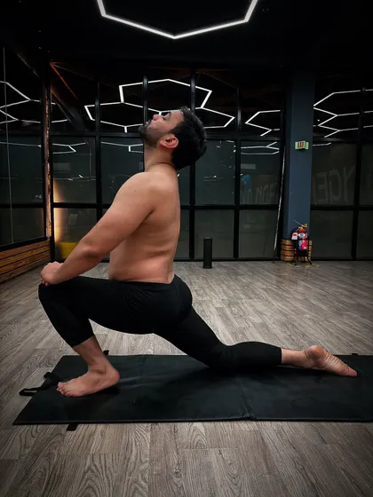 Performing Anjaneyasana (Low Lunge), a deep stretch for the hips and quadriceps. This pose is excellent for improving flexibility and balance.