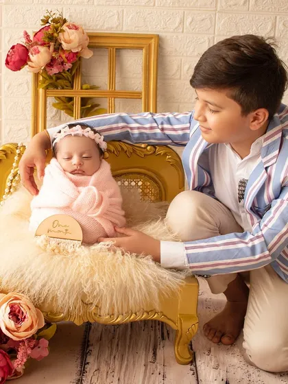 The pride and love of a big brother holding his newborn sister. This is such a heartwarming moment, capturing the beginning of a lifelong bond.