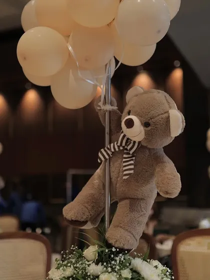 It's all in the details. This adorable teddy bear centerpiece, holding a bunch of balloons, adds a whimsical touch to the guest tables and ties the whole theme together.