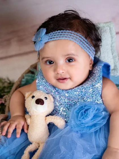 A close-up with her teddy bear, this shot captures the sweet and innocent expression of a six-month-old baby.