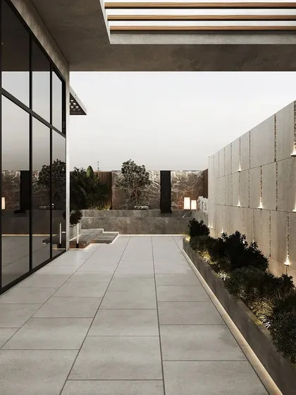 A long view of the rooftop pathway, flanked by illuminated planters and a sleek glass wall, leading towards the main lounge area.