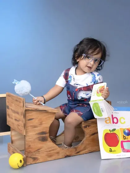 Another take on the 'back to school' theme, this little scholar is engrossed in an ABC book. The setup with a miniature desk and chalkboard is perfect for curious toddlers.