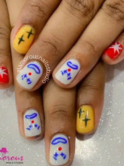 A playful and abstract character design on short nails, using a primary color palette of red, yellow, and blue on a white base.