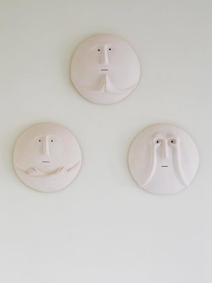 A close-up of the unique, custom-made face sculptures that adorn the dining area wall. These quirky pieces add character and serve as a conversation starter in this otherwise simple space.
