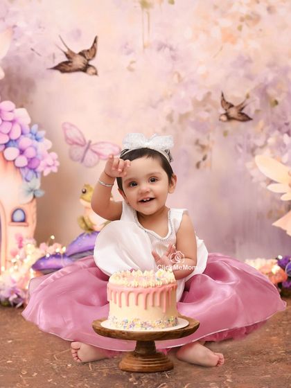 A wave to the camera from our enchanted forest. This little fairy is celebrating her birthday with a delicious cake amidst a whimsical, pastel-colored backdrop.